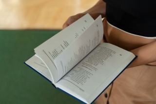 Livre ouvert et doigt suivant une ligne de texte